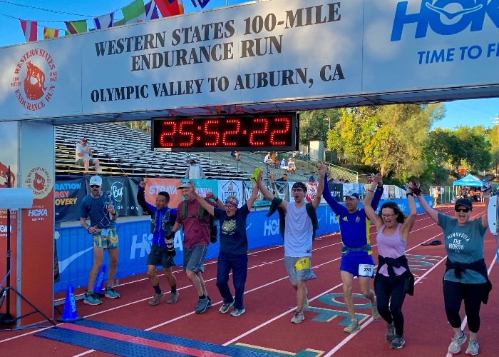 John Maas crossing the finish, his son Taylor pacing, and his family and friends supporting. 
