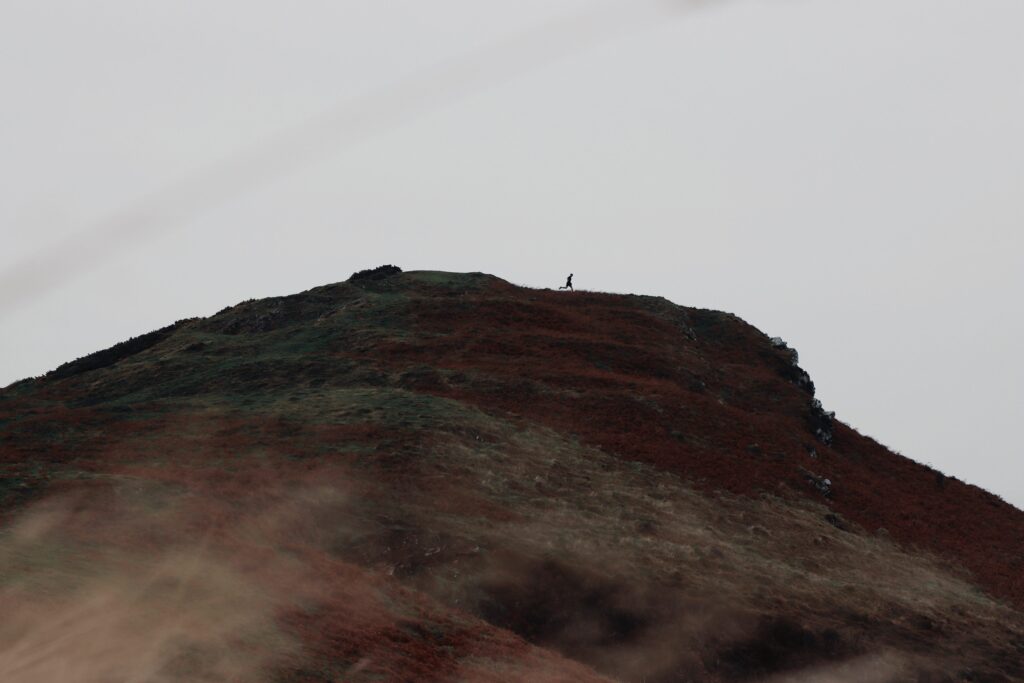 This photo shows the different shades of the Exmoor National Park with a silhouette of a runner skipping across the top of the Little Hangman cliff top.