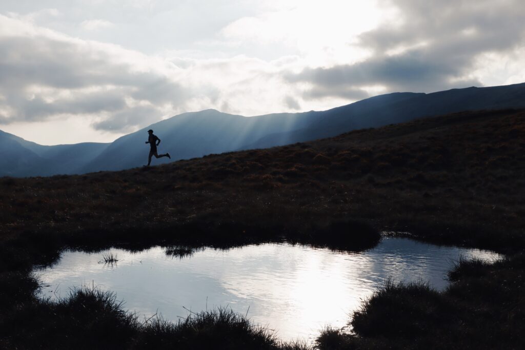 silhouette style photo of a runner (during a race) descending Pen yr Helgi du in Wales