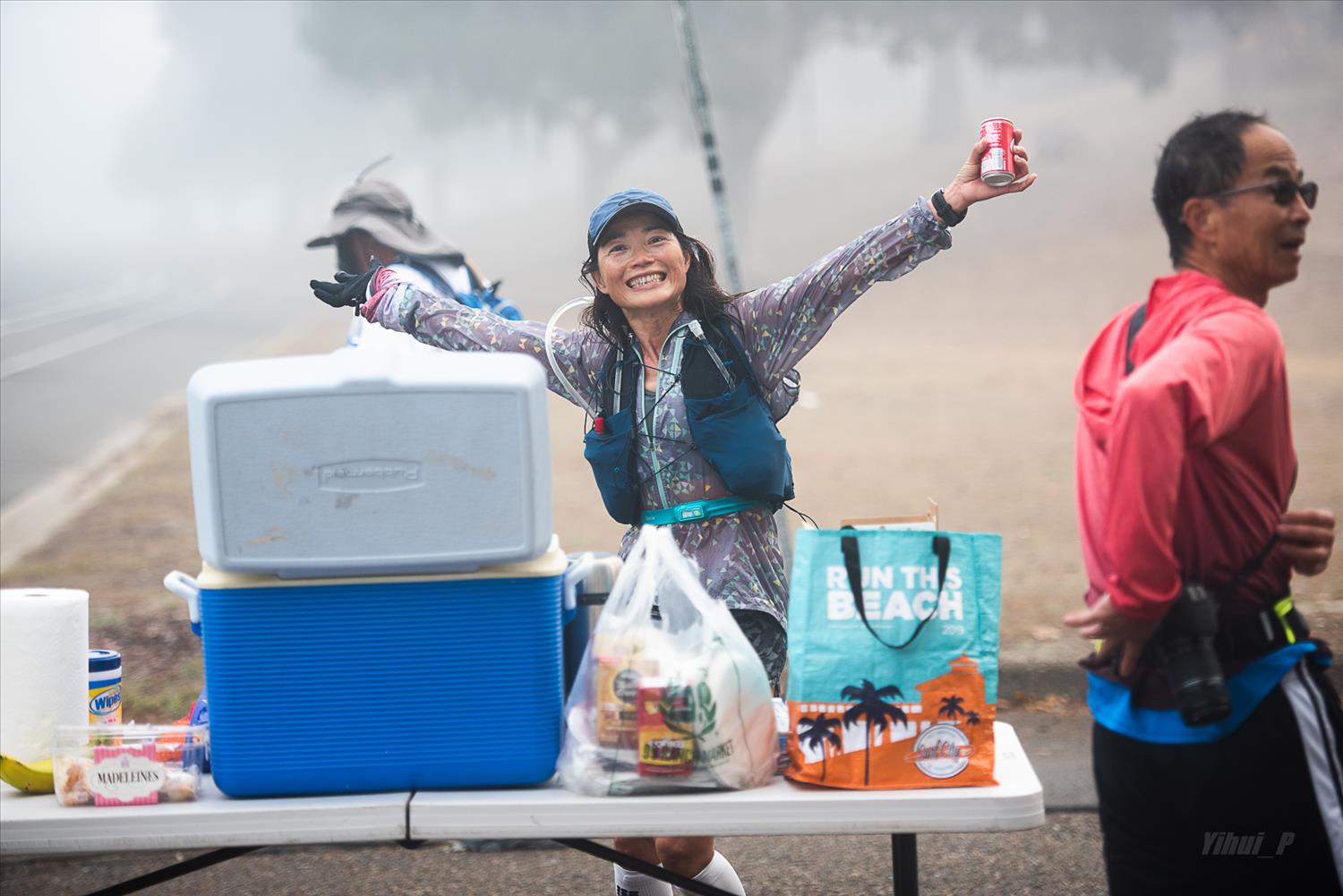 How to not DNF a 100-miler 3 A trail runner smiling at an aid station during an ultramarathon
