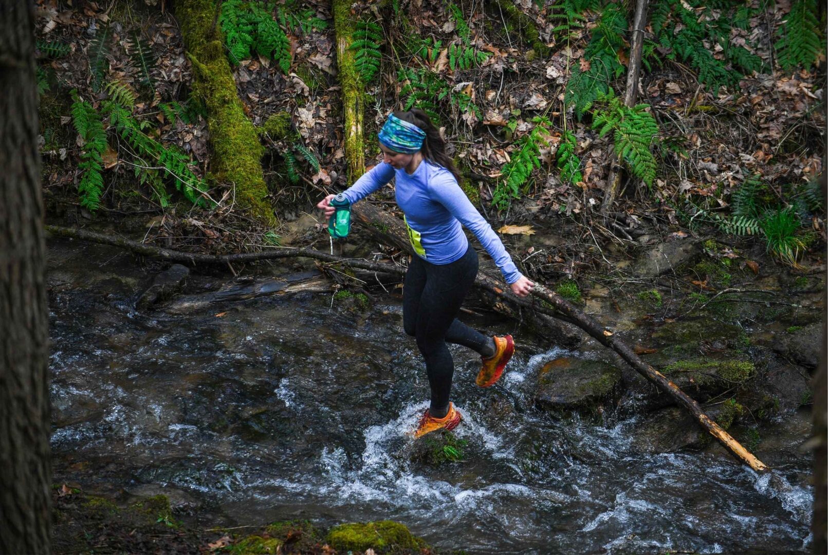 Female trail runner crossing a stream at Eagleton Trail Challenge